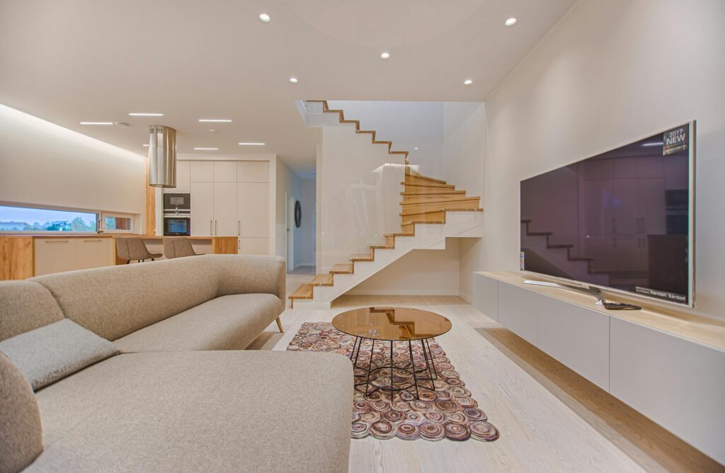 Spacious modern living room featuring stairs, a TV, and sleek furniture design.